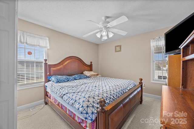 carpeted bedroom featuring multiple windows, ceiling fan, and a textured ceiling