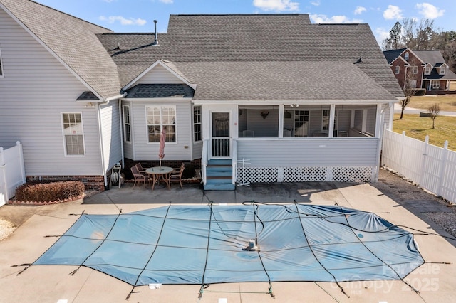 back of property with a sunroom, a covered pool, and a patio area