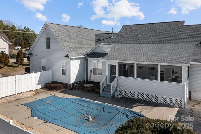 back of property with a covered pool, a patio area, and a sunroom