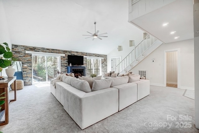 4125 Rivendell Ln, Mint Hill, NC 28227 - carpeted living area featuring visible vents, ceiling fan, stairway, a fireplace, and high vaulted ceiling