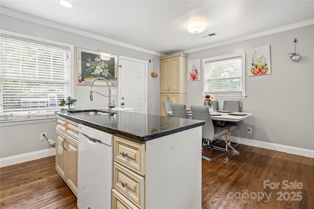 kitchen featuring dishwasher, sink, dark stone counters, cream cabinets, and a center island with sink