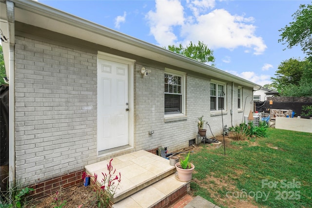 view of exterior entry featuring a lawn