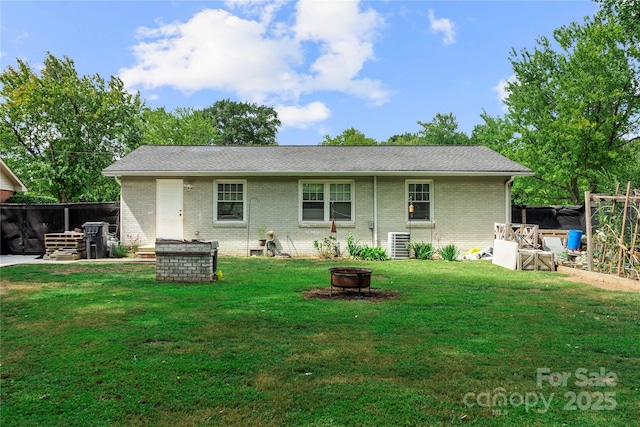 back of house featuring central AC, an outdoor fire pit, and a yard