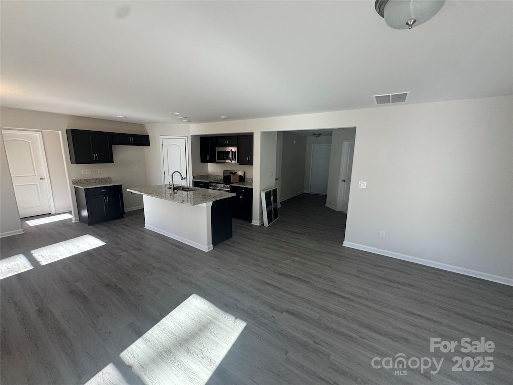 kitchen with appliances with stainless steel finishes, sink, a center island with sink, and dark hardwood / wood-style floors