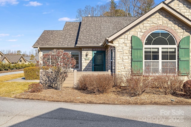 view of front of house with stone siding and a shingled roof