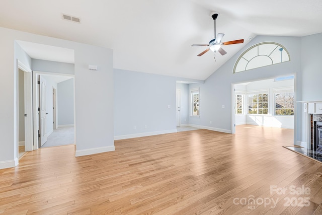 unfurnished living room featuring baseboards, visible vents, a ceiling fan, light wood-style floors, and a high end fireplace