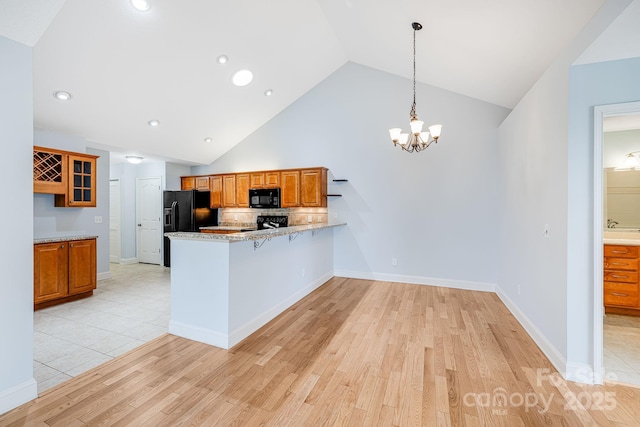 kitchen featuring light wood-style flooring, brown cabinetry, glass insert cabinets, a peninsula, and black appliances