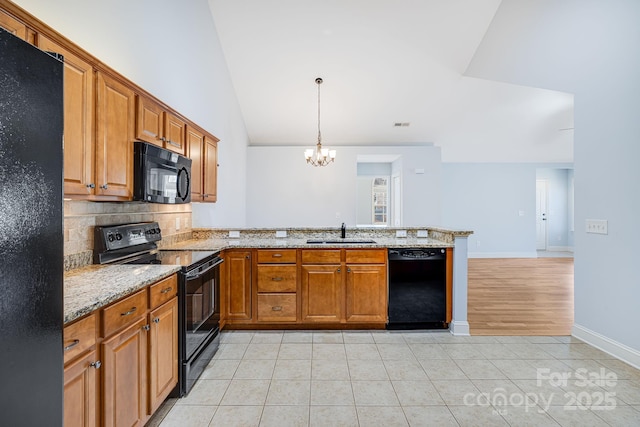 kitchen featuring light stone counters, light tile patterned flooring, a peninsula, a sink, and black appliances