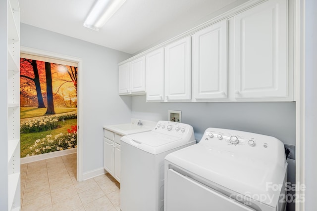 clothes washing area with cabinet space, light tile patterned floors, baseboards, washing machine and dryer, and a sink