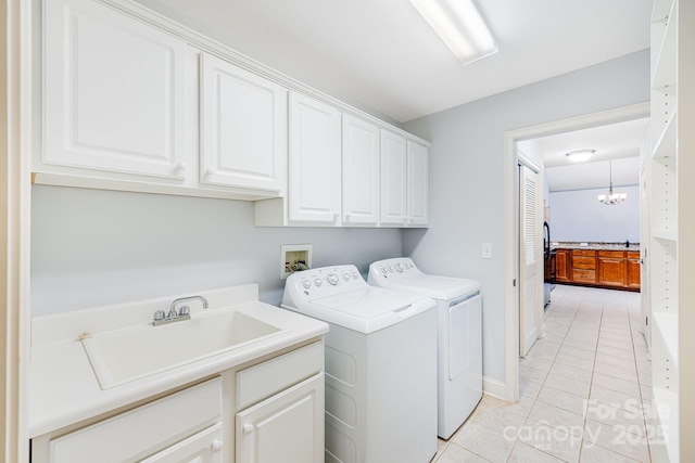 washroom featuring light tile patterned floors, cabinet space, an inviting chandelier, washing machine and dryer, and a sink