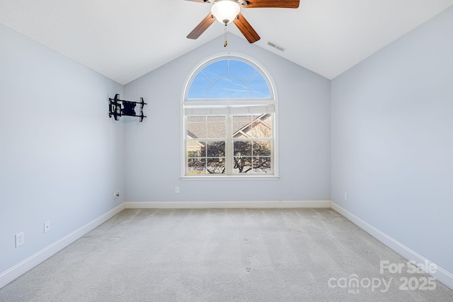 carpeted spare room with a ceiling fan, visible vents, vaulted ceiling, and baseboards