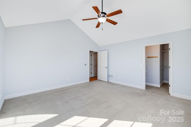 unfurnished bedroom featuring a walk in closet, light colored carpet, ceiling fan, high vaulted ceiling, and baseboards