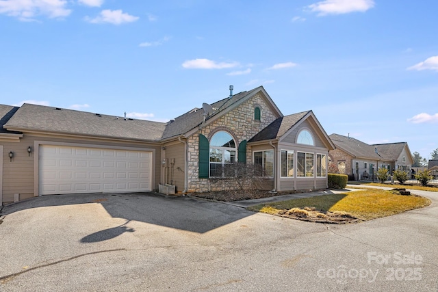 view of front of home with a garage, stone siding, a shingled roof, and aphalt driveway