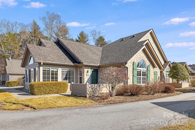 view of front of house featuring stone siding and a shingled roof