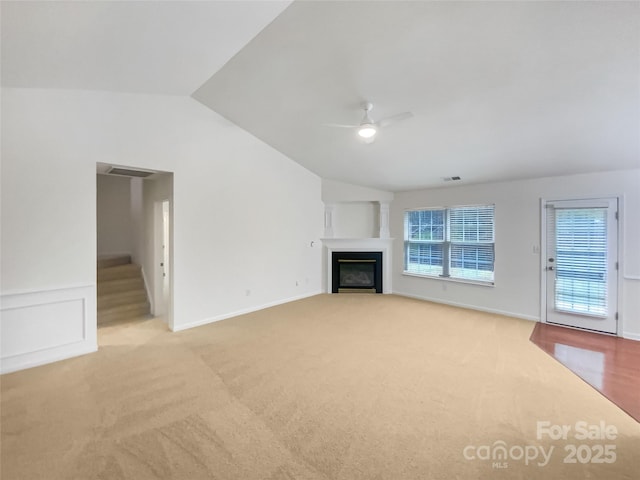 unfurnished living room with vaulted ceiling, light carpet, and ceiling fan