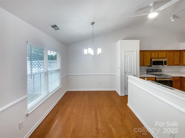 kitchen featuring appliances with stainless steel finishes, pendant lighting, lofted ceiling, and light hardwood / wood-style floors