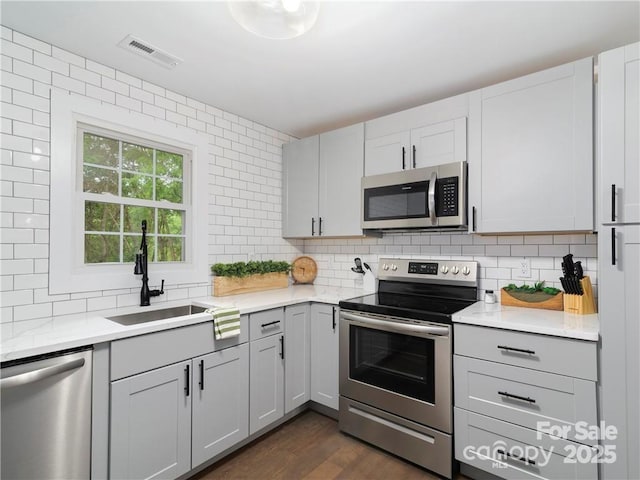 kitchen featuring tasteful backsplash, appliances with stainless steel finishes, sink, and dark hardwood / wood-style floors