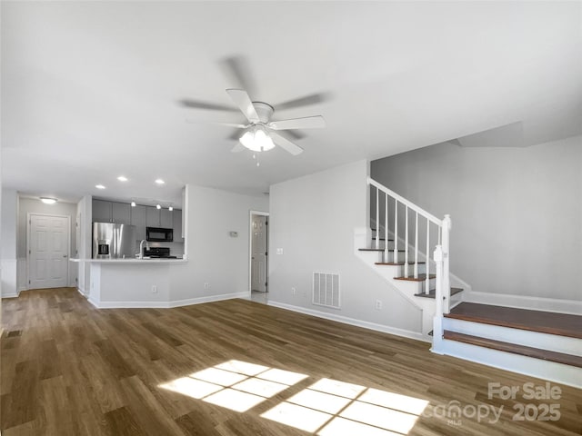 unfurnished living room featuring dark wood-type flooring and ceiling fan