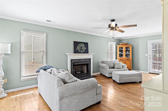 living room with ceiling fan, hardwood / wood-style flooring, ornamental molding, and a textured ceiling