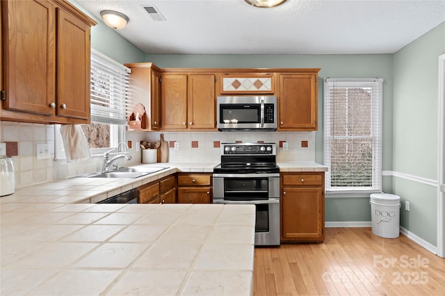 kitchen with stainless steel appliances, tile countertops, sink, and backsplash