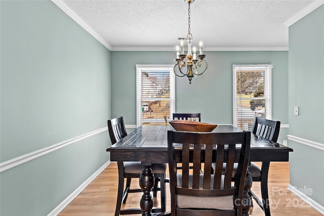 dining space with an inviting chandelier, ornamental molding, a textured ceiling, and light wood-type flooring