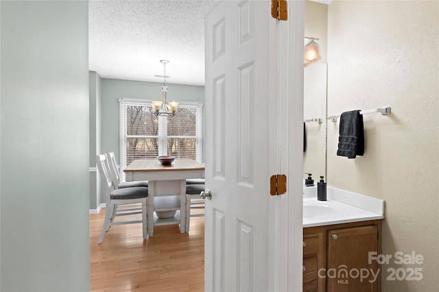 bathroom with vanity, hardwood / wood-style floors, a textured ceiling, and an inviting chandelier