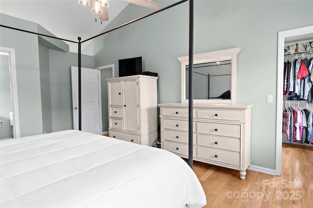 bedroom featuring vaulted ceiling, a walk in closet, light hardwood / wood-style floors, and a closet