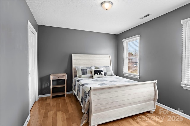 bedroom featuring light hardwood / wood-style flooring, a closet, and a textured ceiling