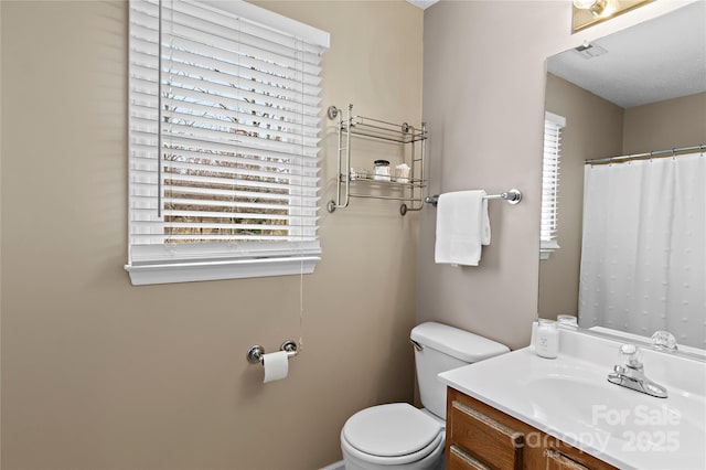 bathroom with vanity, a healthy amount of sunlight, and toilet