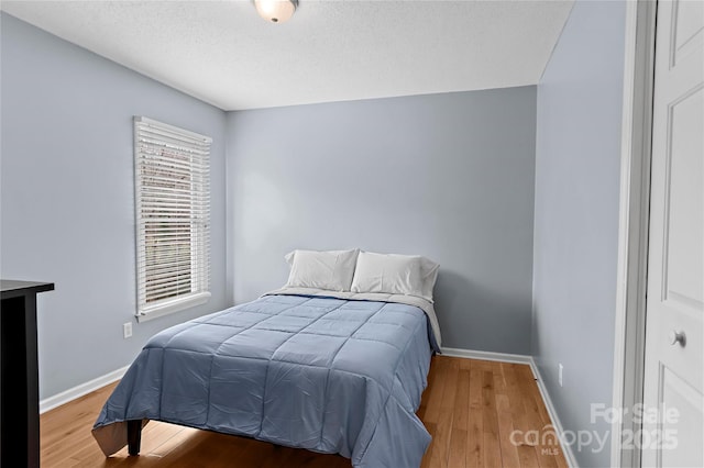 bedroom with hardwood / wood-style floors and a textured ceiling