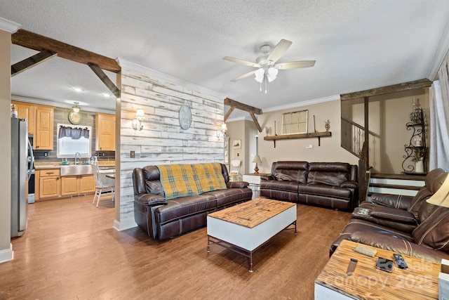 living room featuring sink, crown molding, light hardwood / wood-style flooring, and a textured ceiling