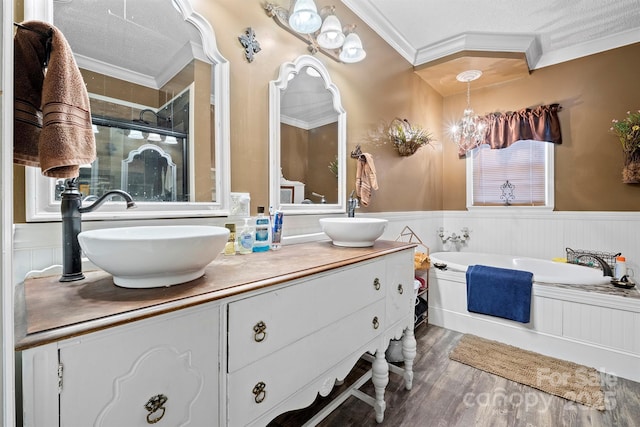 bathroom featuring shower with separate bathtub, hardwood / wood-style floors, vanity, ornamental molding, and an inviting chandelier