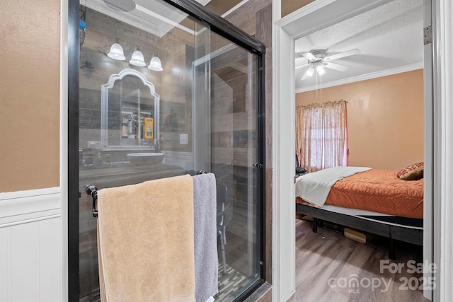 bathroom featuring hardwood / wood-style floors, ornamental molding, ceiling fan, walk in shower, and a textured ceiling