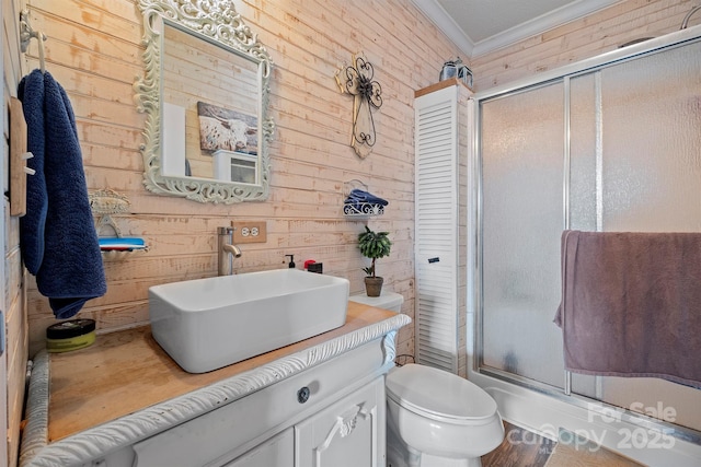 bathroom featuring vanity, toilet, crown molding, and a shower with shower door