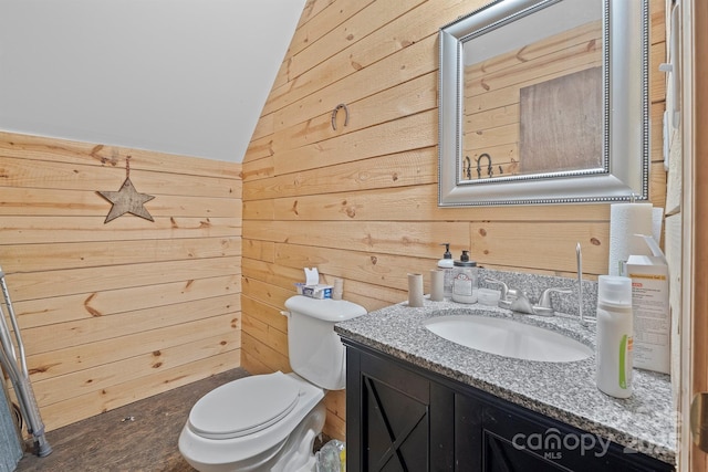 bathroom with vanity, vaulted ceiling, wooden walls, and toilet