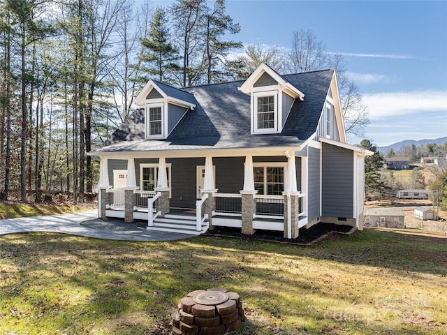 cape cod-style house with a porch, a mountain view, a front yard, and a fire pit