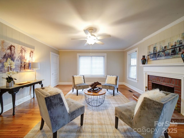 living area with crown molding, a brick fireplace, hardwood / wood-style floors, and ceiling fan