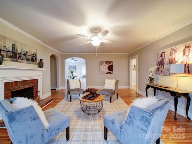 living room with hardwood / wood-style flooring, ornamental molding, and a fireplace