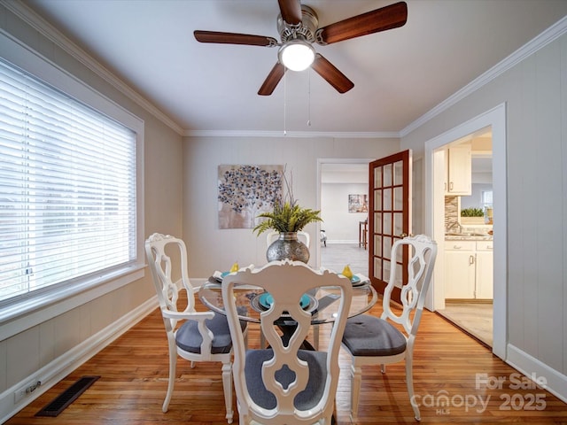 dining space with ornamental molding, light hardwood / wood-style floors, and ceiling fan