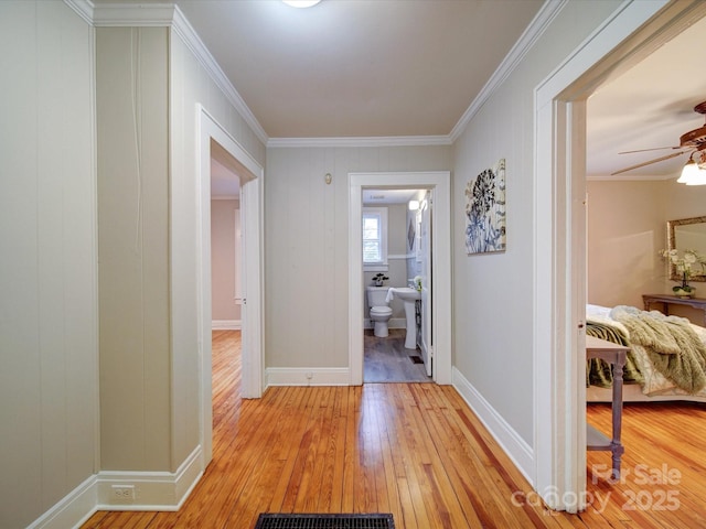 hall with ornamental molding and light hardwood / wood-style flooring