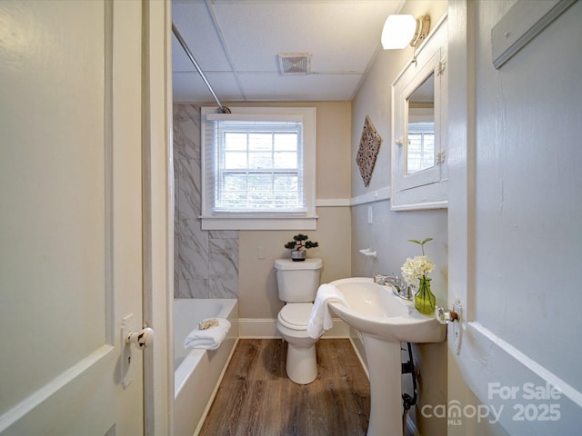 bathroom featuring hardwood / wood-style flooring, shower / tub combination, a drop ceiling, and toilet