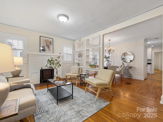 living room featuring a fireplace, a notable chandelier, and wood-type flooring