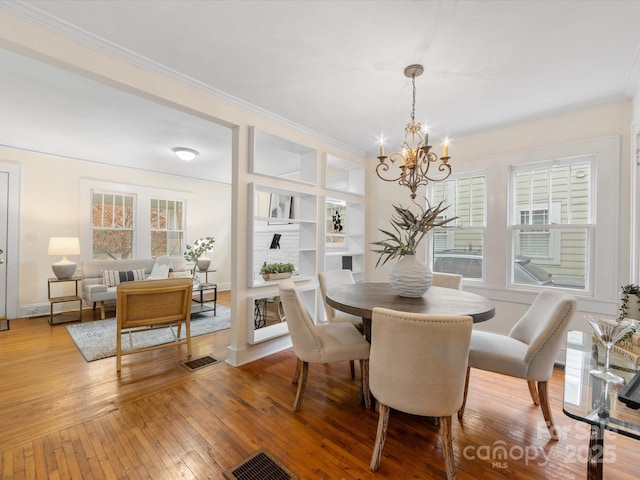 dining space featuring an inviting chandelier, ornamental molding, and light hardwood / wood-style flooring