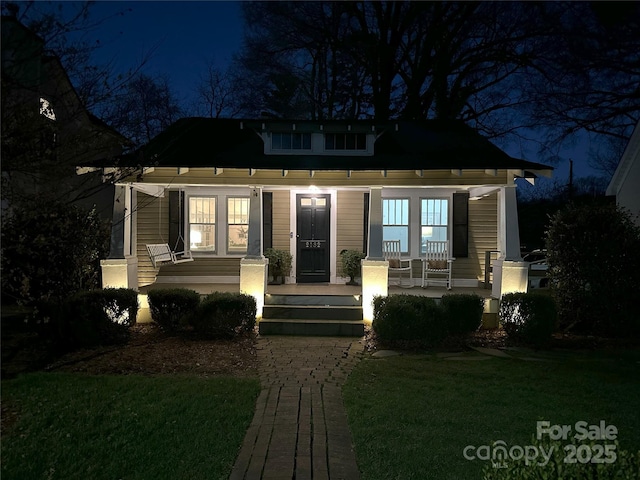 view of front of home with a lawn, french doors, and covered porch