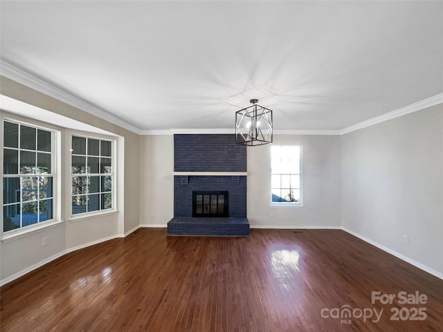 unfurnished living room with crown molding, a brick fireplace, dark hardwood / wood-style floors, and a notable chandelier