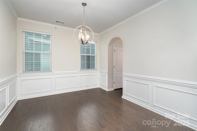 spare room featuring an inviting chandelier, dark hardwood / wood-style flooring, and crown molding