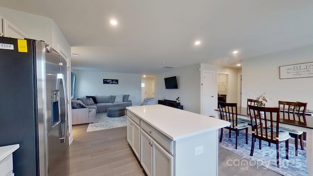 kitchen featuring light hardwood / wood-style flooring, stainless steel fridge with ice dispenser, a kitchen island, and white cabinets