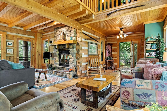 living room featuring a stone fireplace, a healthy amount of sunlight, hardwood / wood-style floors, and wooden ceiling