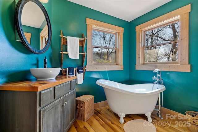 bathroom with wood-type flooring, a healthy amount of sunlight, a bath, and vanity