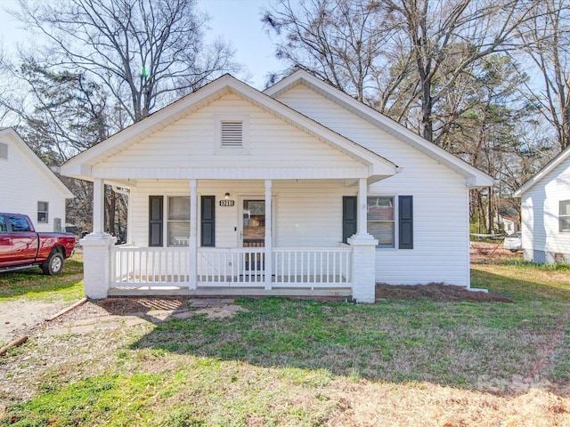 bungalow with covered porch and a front lawn